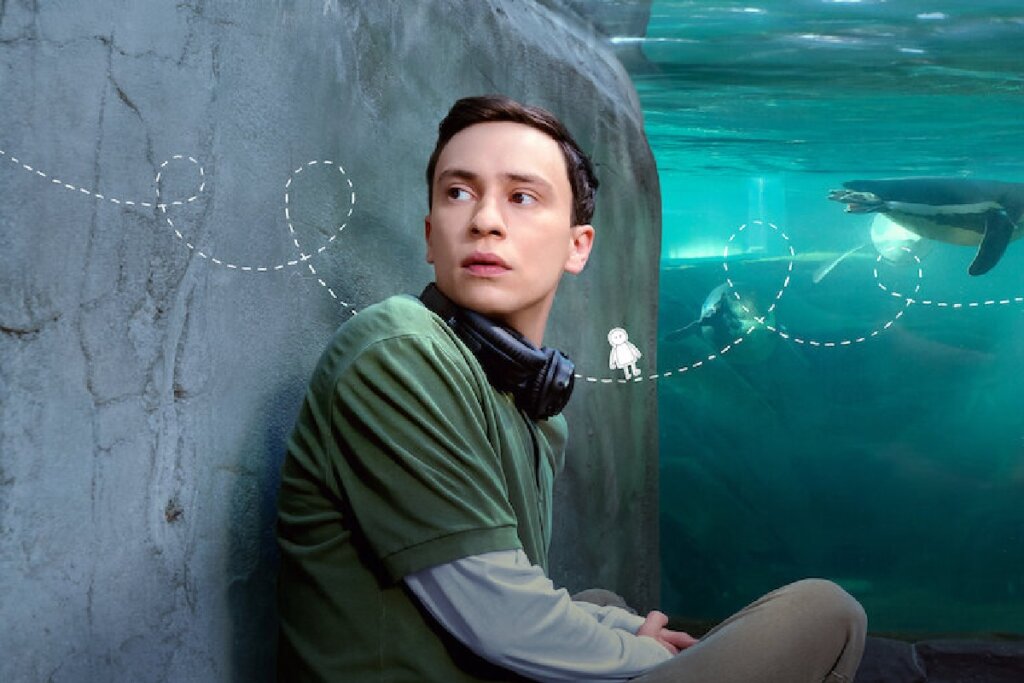 Protagonista da série "Atypical" em frente a um aquário e olhando para o lado