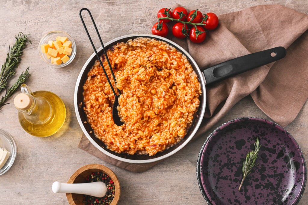 Frigideira com risoto de tomate e outros itens sob a mesa