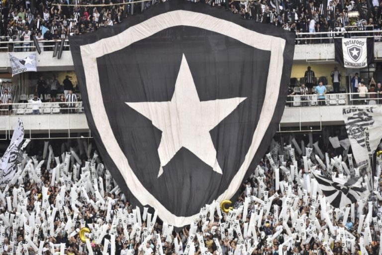 bandeira grande com brasão do botafogo estendida sobre arquibancada em estádio