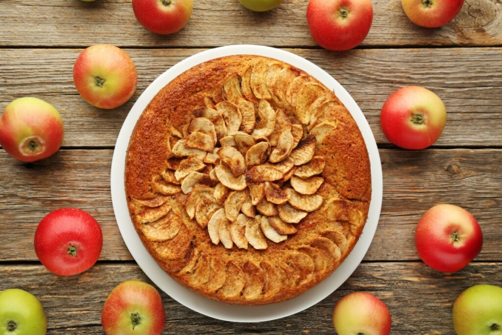 Travessa branca com bolo de maçã com banana, decorado com rodelas de maçã e polvilhado com canela em pó