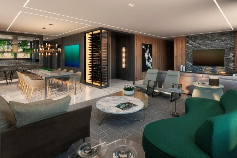 Sala de estar em conceito aberto, com um sofá cinza em destaque, poltronas da mesma cor posicionadas ao fundo e uma mesa de centro branca à frente