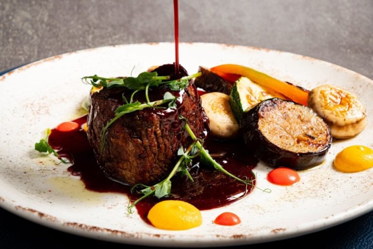 Prato branco com filé-mignon com molho e vegetais grelhados 