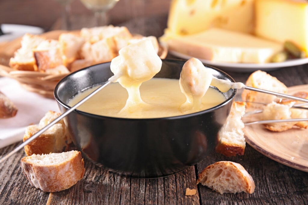 Fondue de queijo em uma panela preta em cima deu ma mesa de madeira