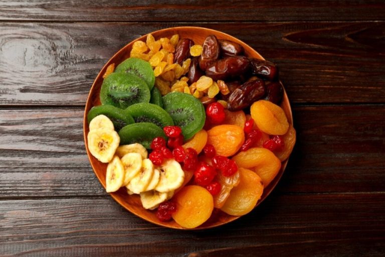 Prato de madeira com frutas secas coloridas como banana, kiwi, damasco, uva-passa e cereja