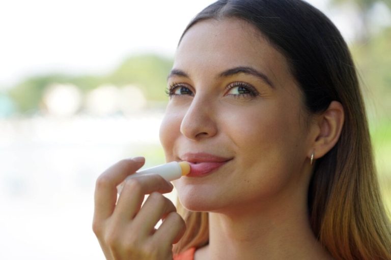 Mulher sorrindo e passando lip balm na boca