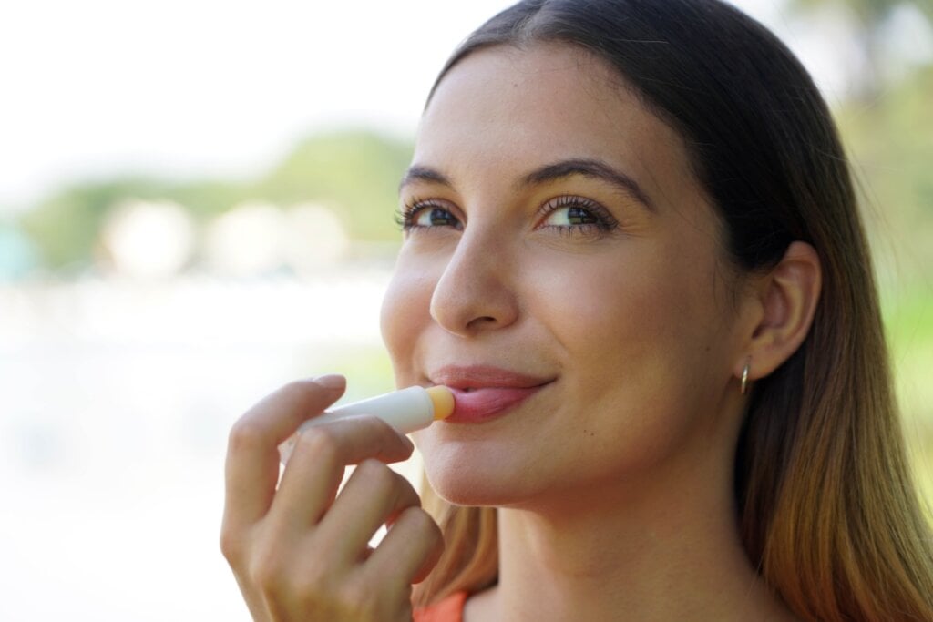 Mulher sorrindo e passando lip balm na boca