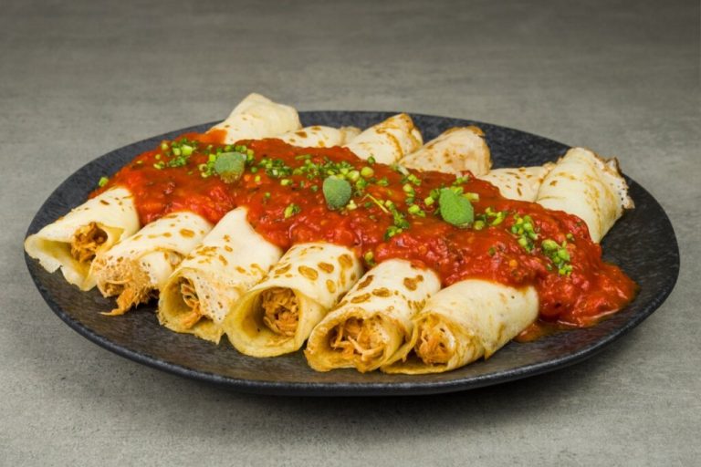 Panquecas de frango sem glúten cobertas com molho de tomate encorpado e decoradas com ervas frescas, servidas em prato escuro