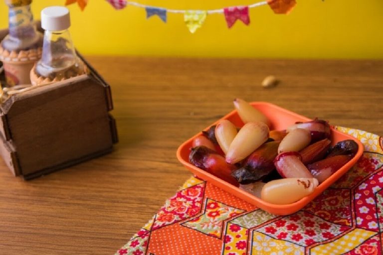 Porção de sementes de pinhão cozidas servidas em recipiente laranja em ambiente decorado com temática de festa junina