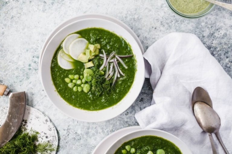 Sopa de agrião com abobrinha em um prato branco em cima de uma mesa de mármore 
