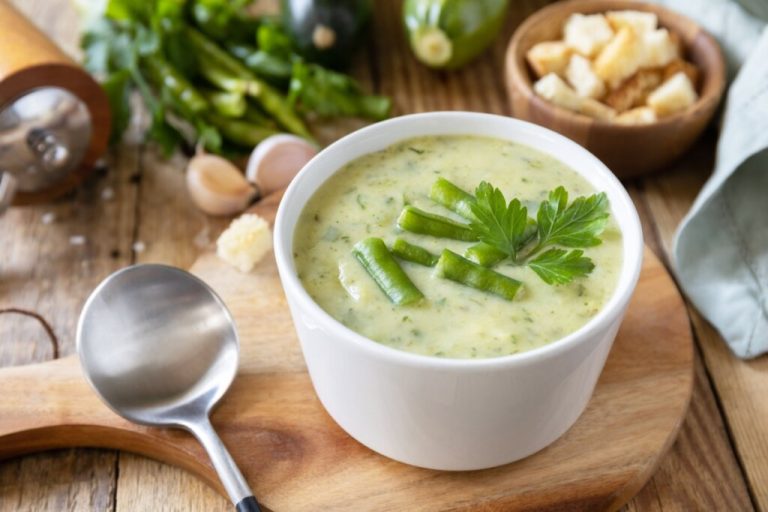 Recipiente branco com sopa de feijão-verde com abobrinha