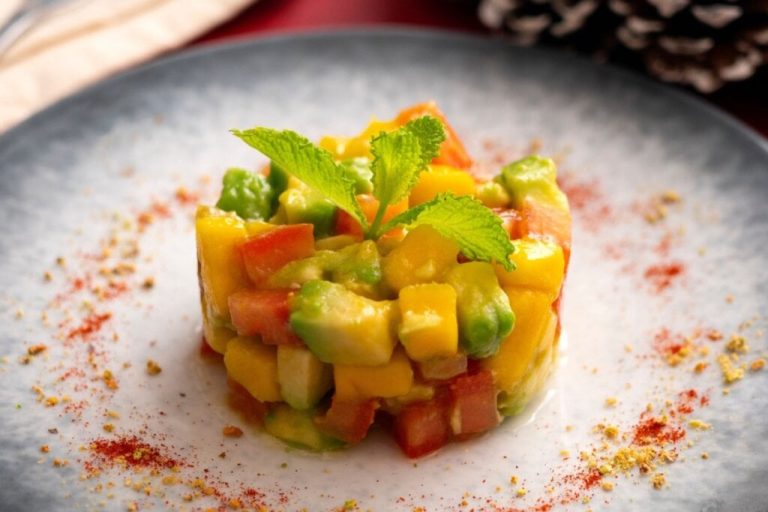 Tartar de abacate com manga e tomate em um prato branco 