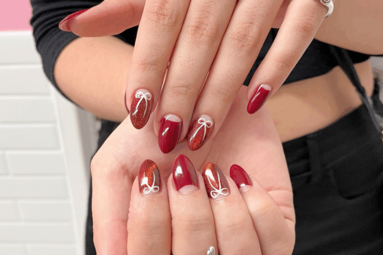 duas mãos com unhas em tons de vermelho e marrom e desenhos de laços