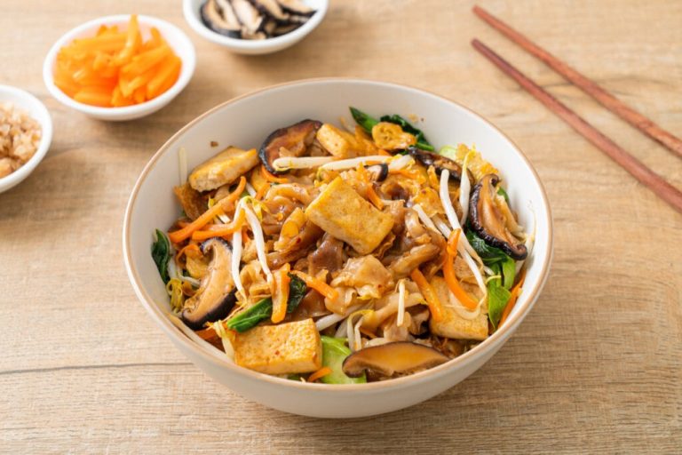 Yakissoba com tofu, espinafre, macarrão, cogumelos e cenoura em um recipiente branco
