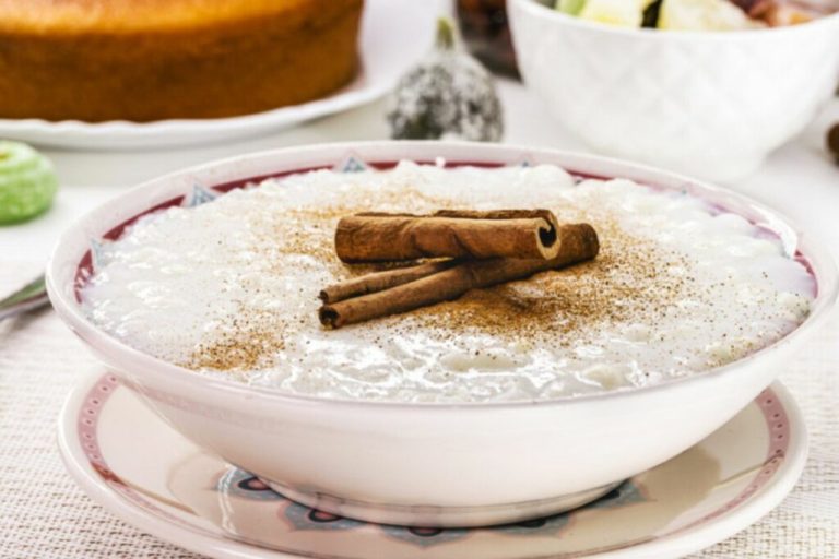 Canjica em um recipiente branco decorada com canela em pó e em paus