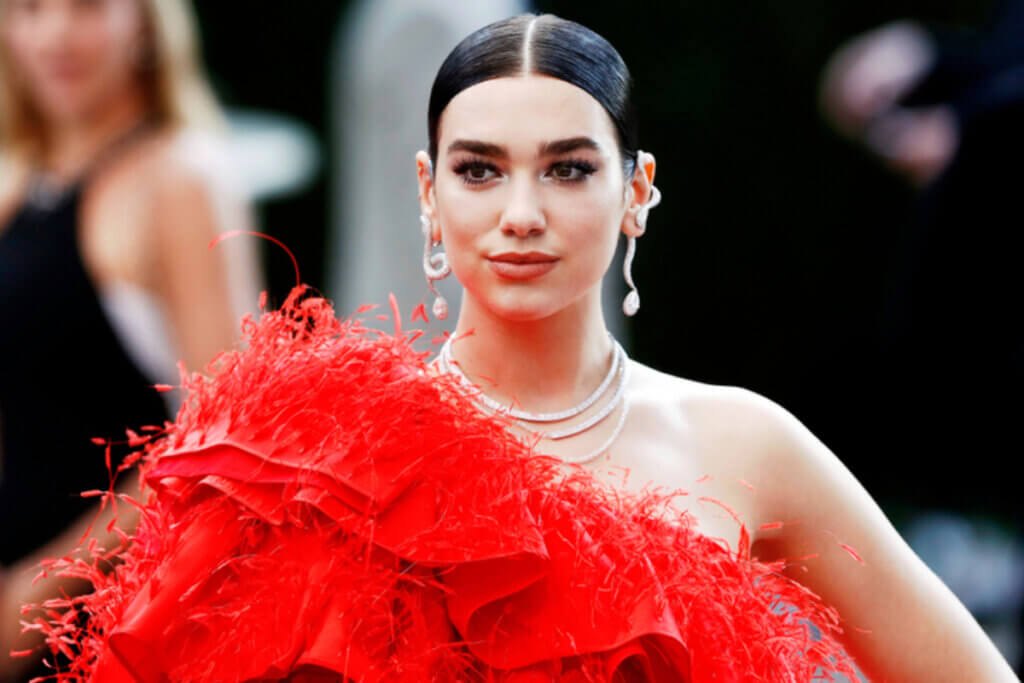 Mulher com o cabelo preso com gel, usando vestido vermelho com plumas
