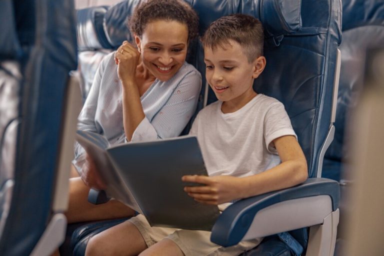 Mulher e menino sentados em uma cadeira de avião lendo livro 