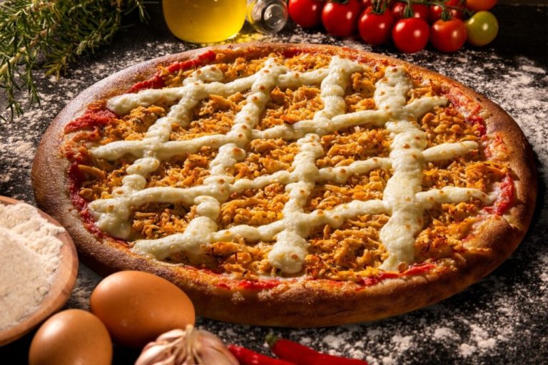 Pizza de frango com requeijão em uma mesa de madeira enfarinhada com farinha de trigo