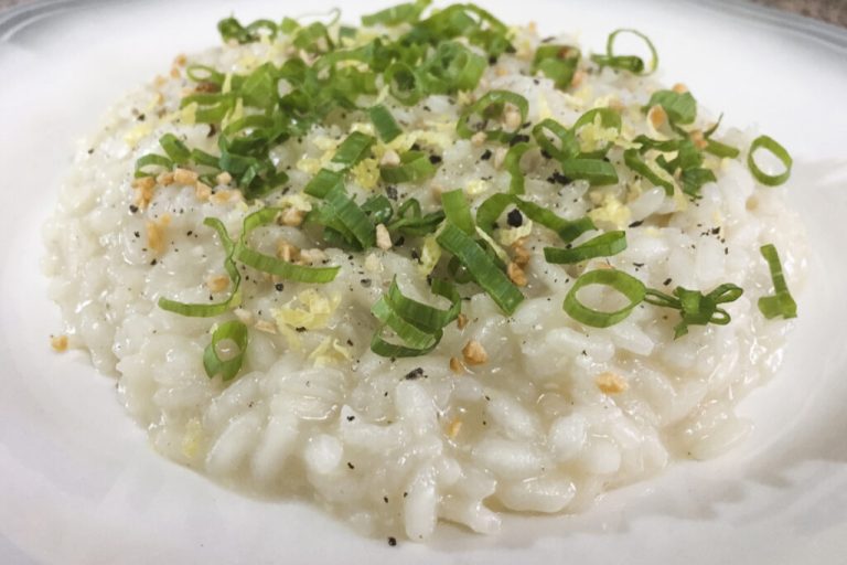 Prato branco com risoto decorado com cebolinha e castanhas picadas