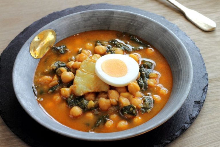 Sopa de grão-de-bico com espinafre e bacalhau em prato fundo cinza