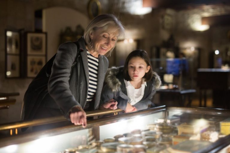Mulher e menina em um museu olhando algo exposto embaixo de um vidro 