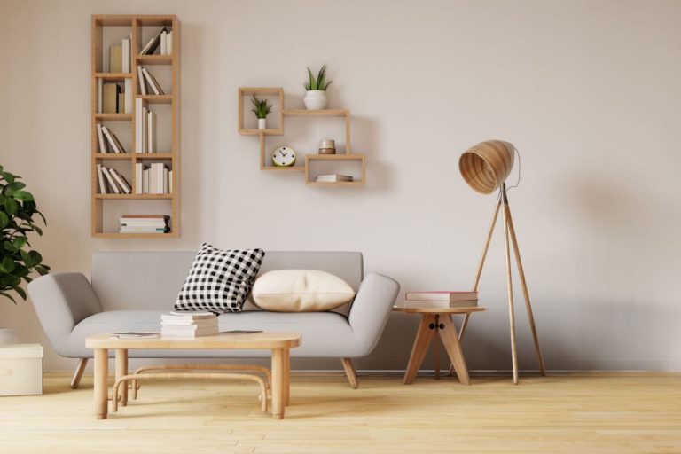 Sala de estar com parede branca, sofá cinza, mesa de centro e alguns itens de decoração de madeira