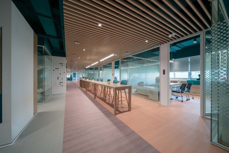 Hall de um escritório com mesa, chão e teto revestidos com madeira