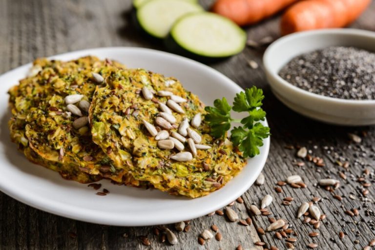 Duas panquecas de legumes com chia em um prato branco e decoradas com sementes de girassol