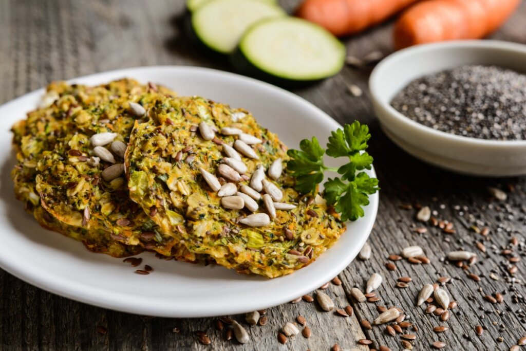 Duas panquecas de legumes com chia em um prato branco e decoradas com sementes de girassol