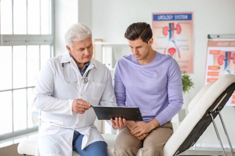 Médico explicando algo para um homem em um tablet, ambos sentado em um consultório 