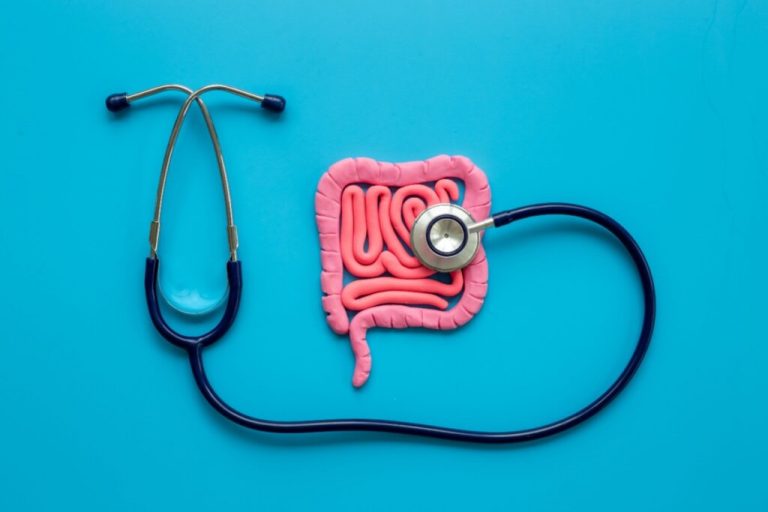 Ilustração de um intestino em rosa sendo examinado com um estetoscópio preto em fundo azul 