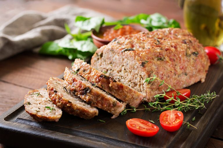 Bolo de carne com pedaços de cheiro-verde em cima de tábua preta