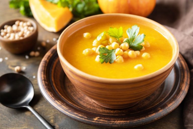 Bowl fundo com sopa cremosa de abóbora com grão-de-bico cozido e folhas de salsa