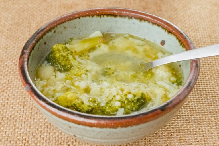 Sopa de brócolis com couve-flor em tigela de cerâmica em cima de mesa com toalha de estopa 