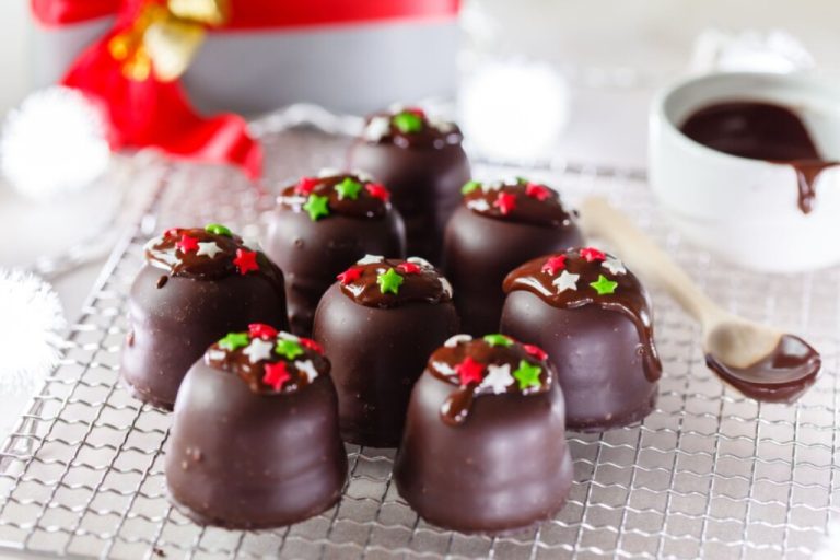 Marias-moles com cobertura de chocolate sobre uma grade de metal branca, decoradas com confeitos em formato de estrela