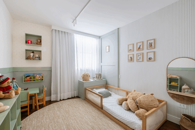Quarto com decoração clara, e parte de uma parede em verde e com móveis de madeira clara e verde, com cama montessoriana, espelho na parede e tapete bege