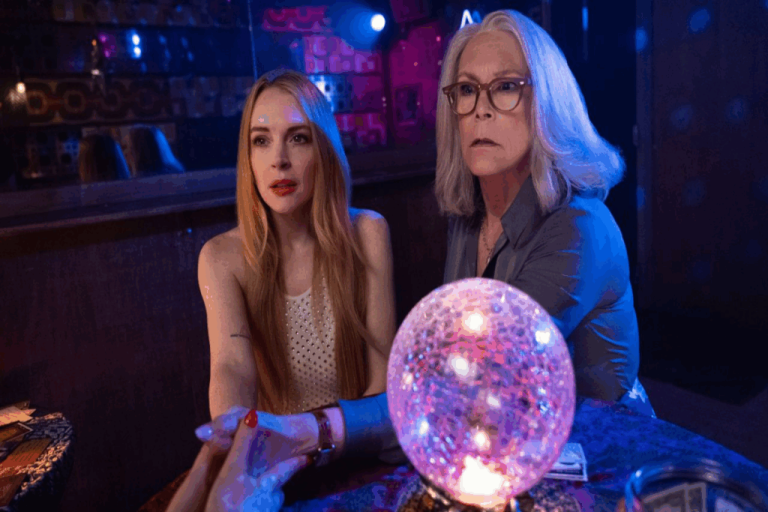 Duas mulheres, uma jovem e uma mais velha tendo suas mãos  lidas, em uma mesa com uma bola de cristal