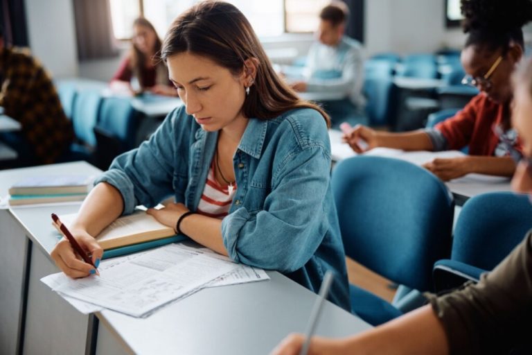 Menina sentada em uma sala de aula fazendo prova