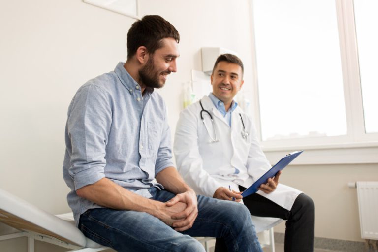 Homem em consulta médica; o paciente e o profissional estão sentados em maca