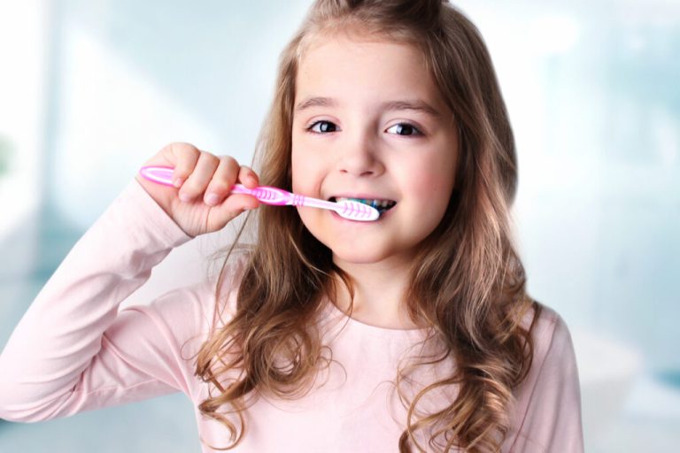 Menina sentada escovando os dentes 